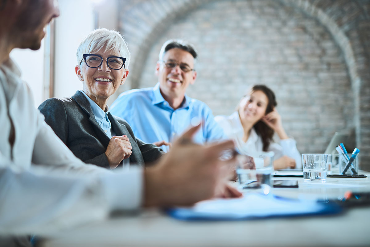 Business employees in a conference excitedly listen to a coworker.