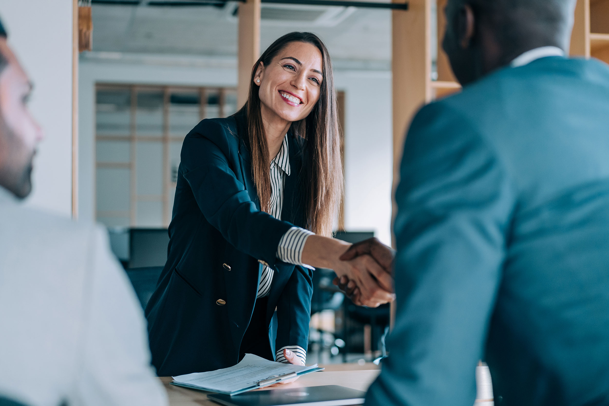 An executive shakes hands with a client signifying a successful partnership.